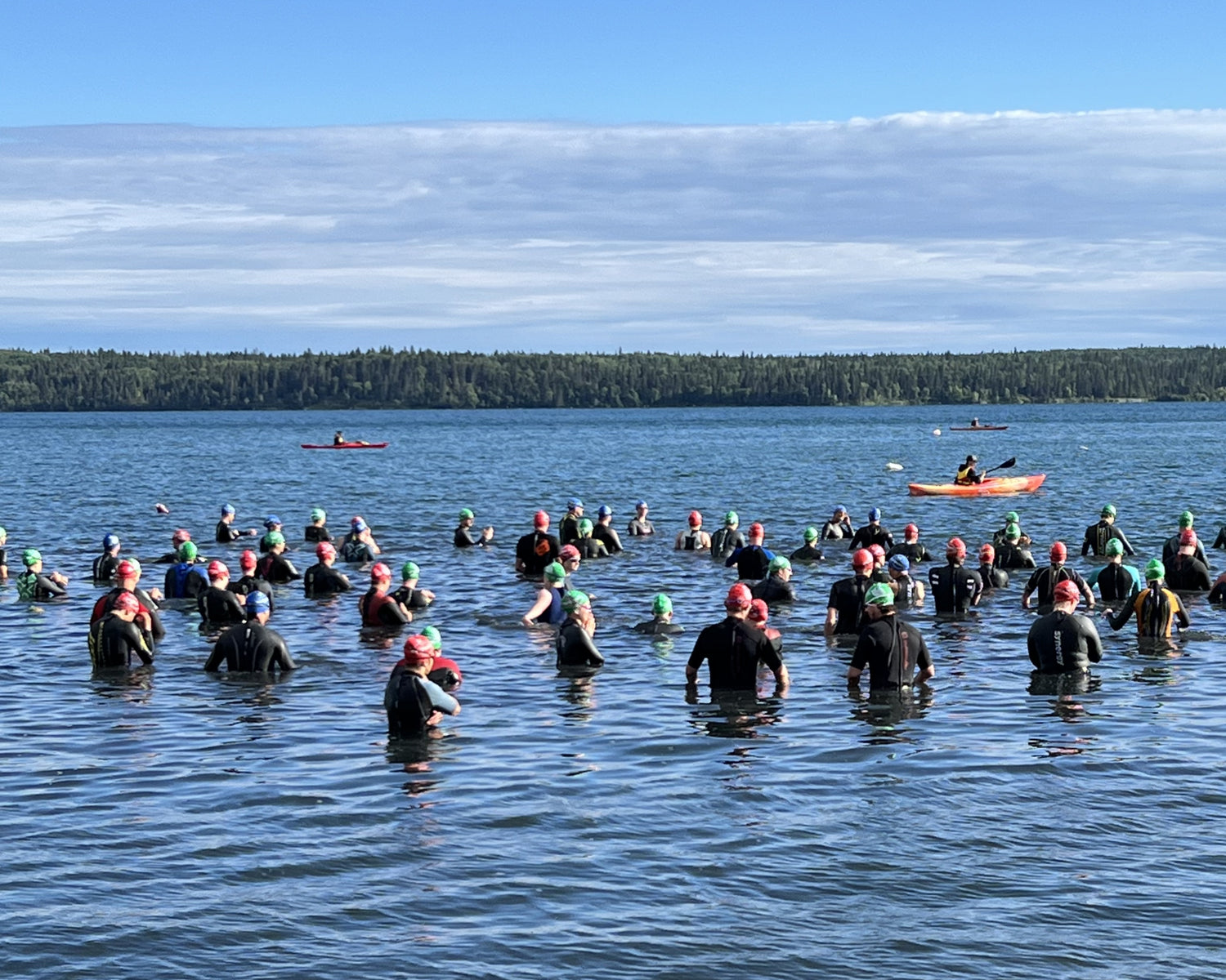 Group of people participating in a swim event with kayaks in the background